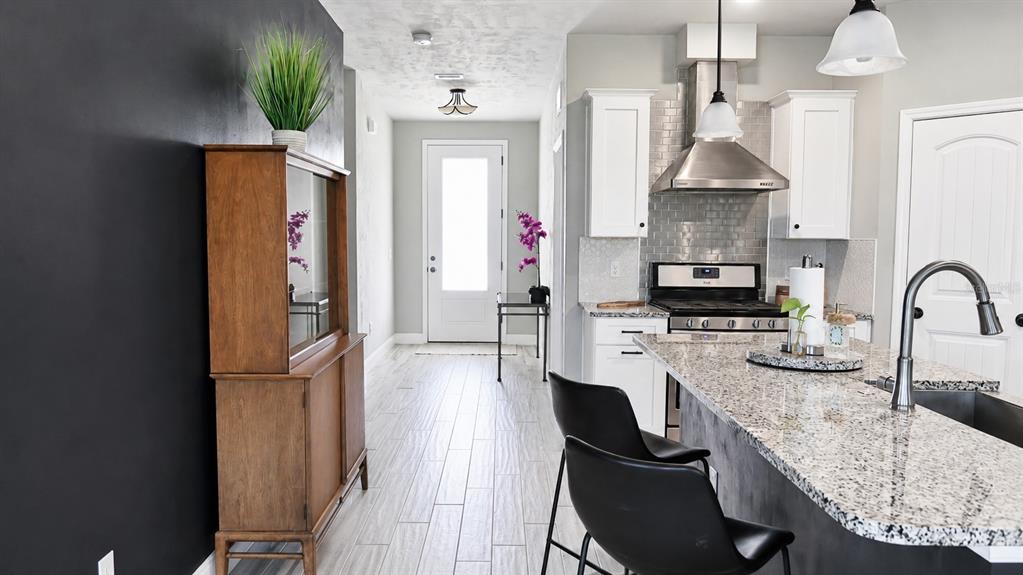 A kitchen with granite countertops, white cabinets, and a black accent wall leads to an entryway — 1960 SW 247TH WAY, NEWBERRY, FL