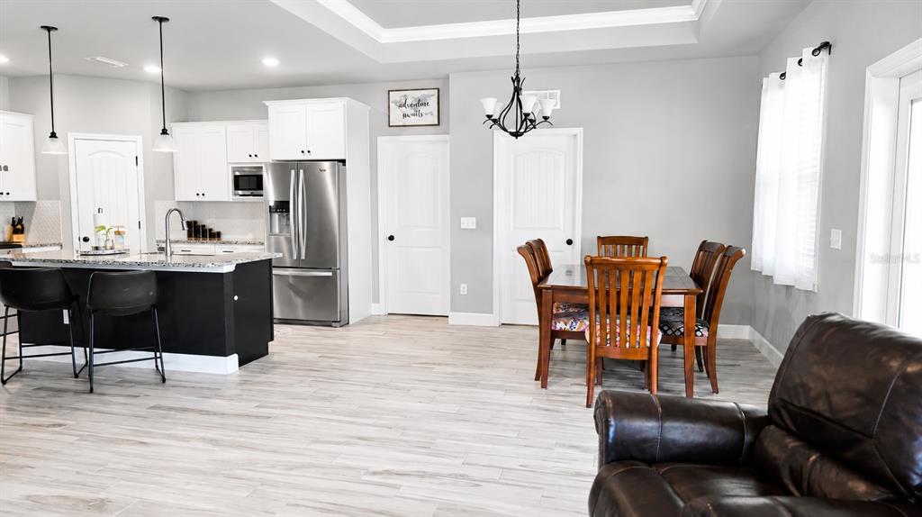 A kitchen with a dark island and stainless steel appliances opens to a dining area — 1960 SW 247TH WAY, NEWBERRY, FL