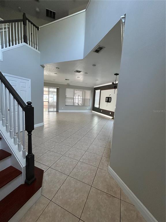 An open-concept living area features tile flooring, a staircase with dark wood treads, and recessed lighting — 1278 SNUG HARBOR DRIVE, CASSELBERRY, FL
