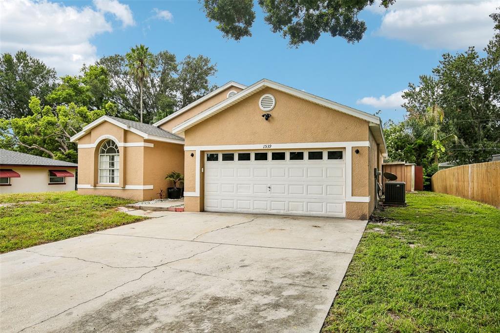 A single-story tan house with a two-car garage and a concrete driveway — 1539 VALENCIA STREET, CLEARWATER, FL