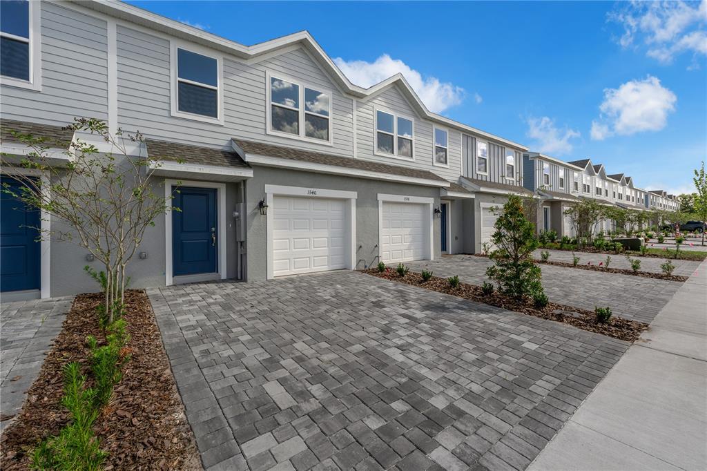 A row of modern townhouses features gray siding, white garage doors, and paved driveways — 3016 JESSAMINE DRIVE, TAVARES, FL