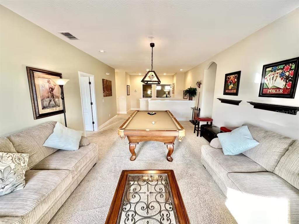 A game room features a pool table, two sofas, and wall art on carpeted floors — 4353 ACORN COURT, DAVENPORT, FL