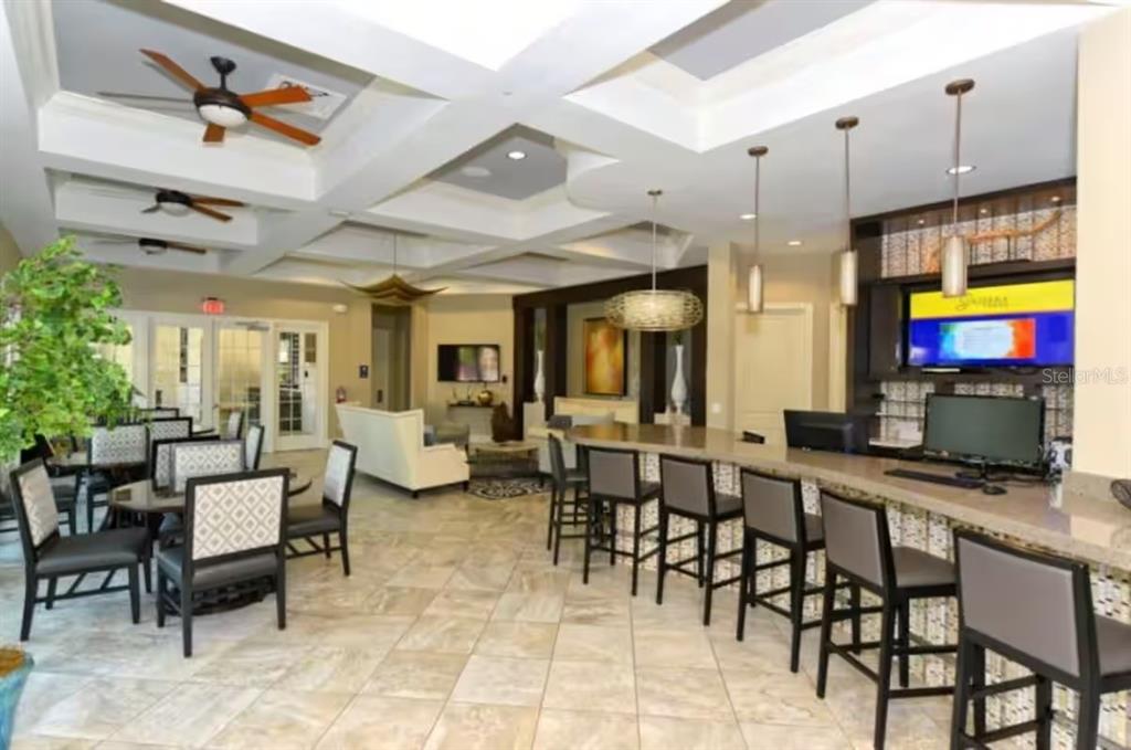 A spacious clubhouse lounge features a long bar, dining tables, and a coffered ceiling — 4353 ACORN COURT, DAVENPORT, FL
