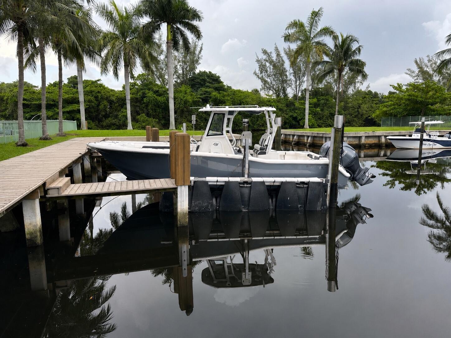 A gray center console boat is docked in a canal lined with palm trees — 4400 Hidden Harbour Terrace, Dania Beach FL 33312, DANIA BEACH, FL