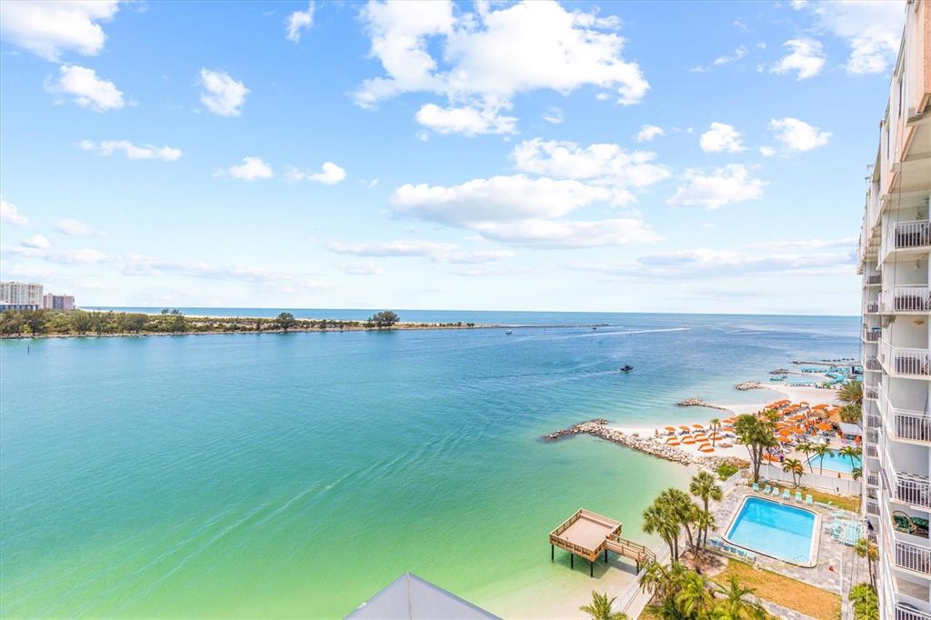 An elevated view of a coastal resort featuring a swimming pool, beach, and ocean inlet — 691 S GULFVIEW BOULEVARD UNIT 815, CLEARWATER BEACH, FL