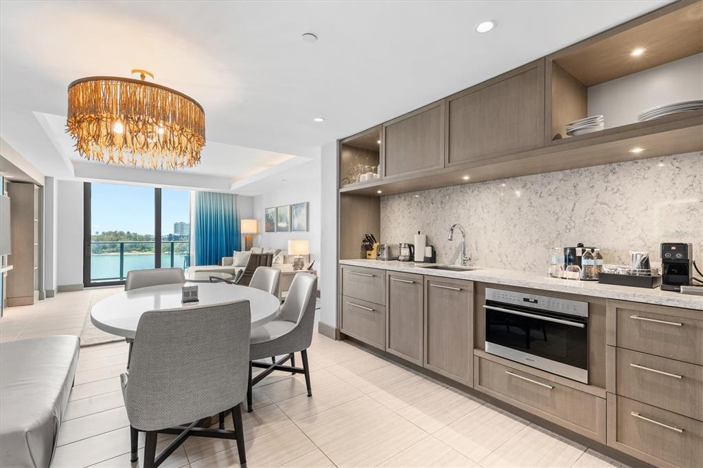 A modern kitchen and dining area features wood cabinetry, stone countertops, and a water view — 691 S GULFVIEW BOULEVARD UNIT 815, CLEARWATER BEACH, FL