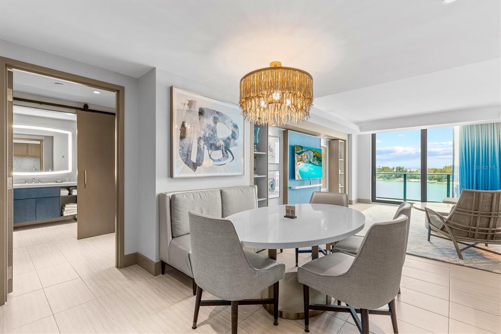 A dining area with a round table, upholstered chairs, and a bench near a balcony — 691 S GULFVIEW BOULEVARD UNIT 815, CLEARWATER BEACH, FL