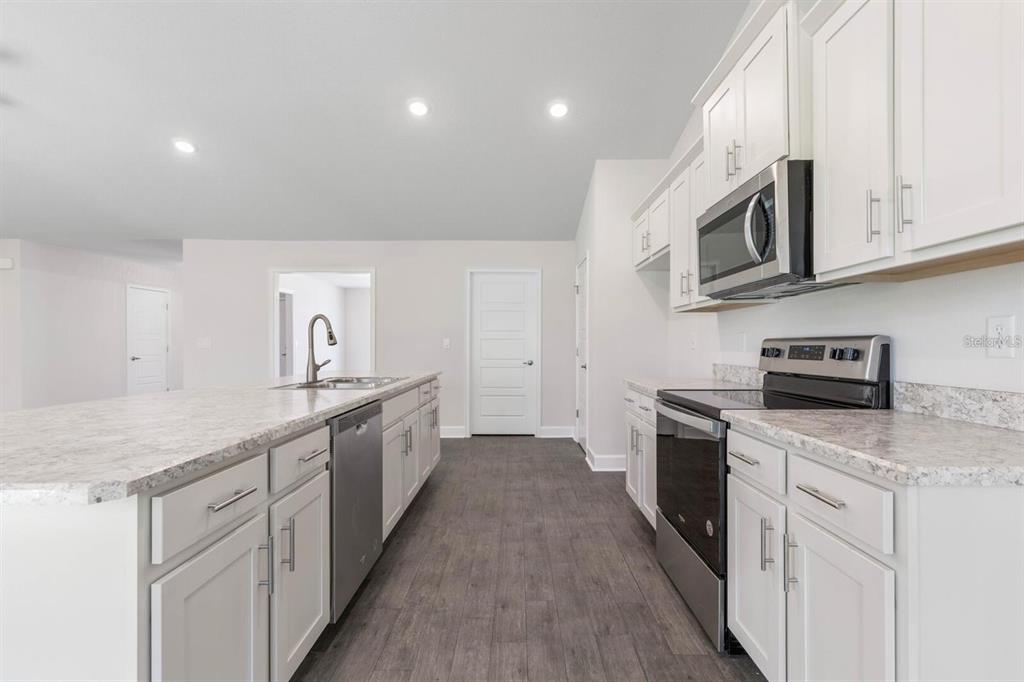 A kitchen with white cabinets, stainless steel appliances, and a large island with a sink — 34 RYMSHAW DRIVE, PALM COAST, FL