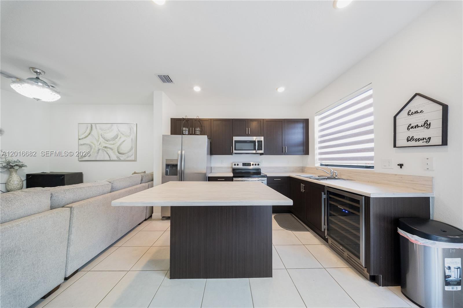 A kitchen features dark wood cabinets, a central island, stainless steel appliances, and tile flooring — 18236 SW 148th Rd, Miami FL 33187, MIAMI, FL