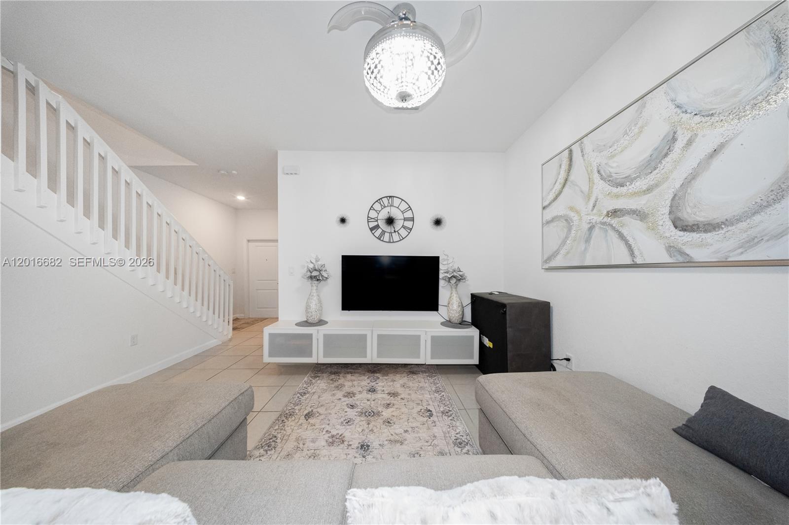 A living room features a wall-mounted television, a white media console, and a staircase — 18236 SW 148th Rd, Miami FL 33187, MIAMI, FL