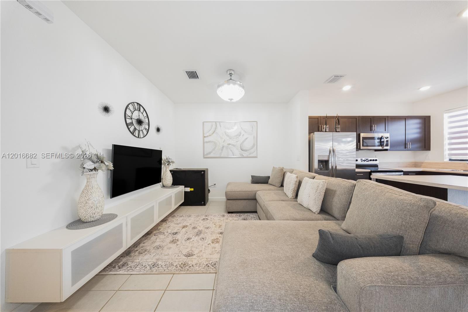 A living room features a large sectional sofa, a wall-mounted television, and an open kitchen — 18236 SW 148th Rd, Miami FL 33187, MIAMI, FL