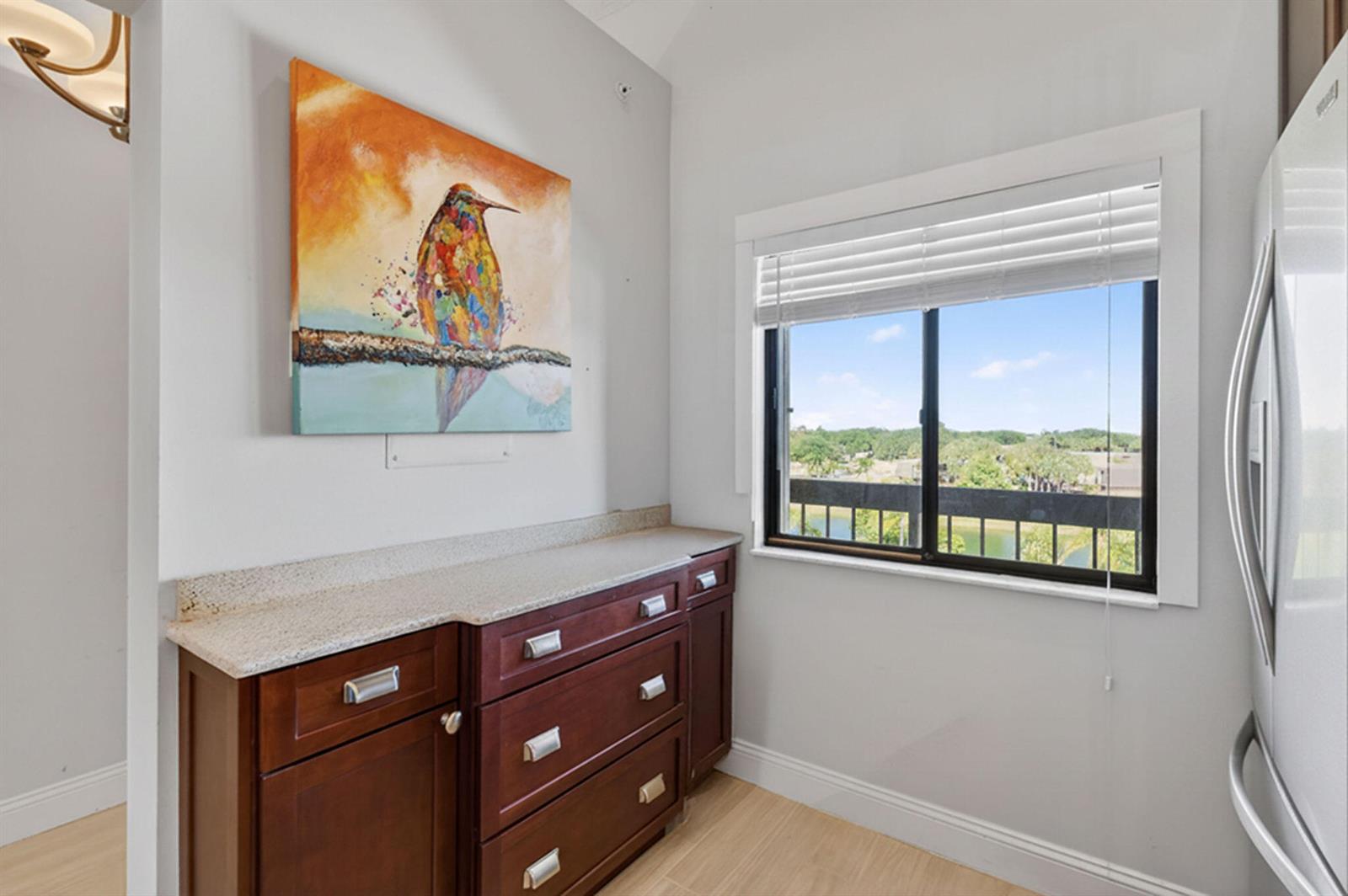 A small room features dark wood cabinetry, a granite countertop, and a window with views — 701 Seafarer Circle # 504, Jupiter FL 33477, JUPITER, FL