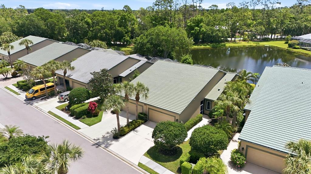 An aerial view shows a row of attached houses with green roofs near a pond — 8549 54TH AVENUE CIRCLE E, BRADENTON, FL