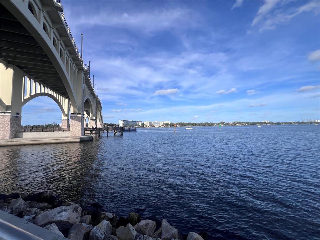 A concrete bridge spans over a body of water with a distant shoreline under clouds — 1224 S PENINSULA UNIT 304, DAYTONA BEACH, FL