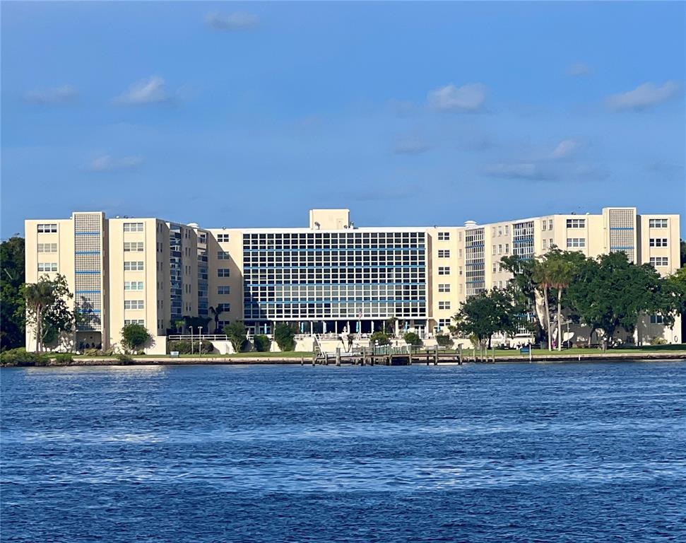 A large, multi-story apartment building sits along a waterfront with a dock and trees — 1224 S PENINSULA UNIT 304, DAYTONA BEACH, FL