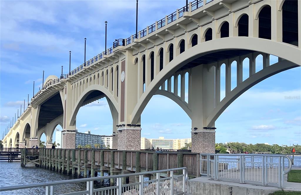 A concrete arched bridge spans over a wooden pier and water under a blue sky — 1224 S PENINSULA UNIT 304, DAYTONA BEACH, FL