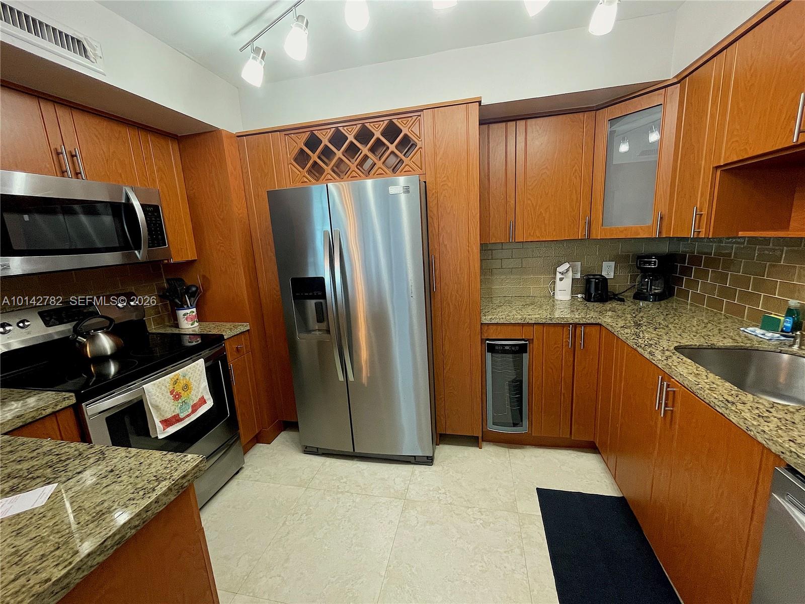A kitchen features wood cabinets, stainless steel appliances, granite countertops, and a wine cooler — 3505 S Ocean Dr # 1415, Hollywood FL 33019, HOLLYWOOD, FL
