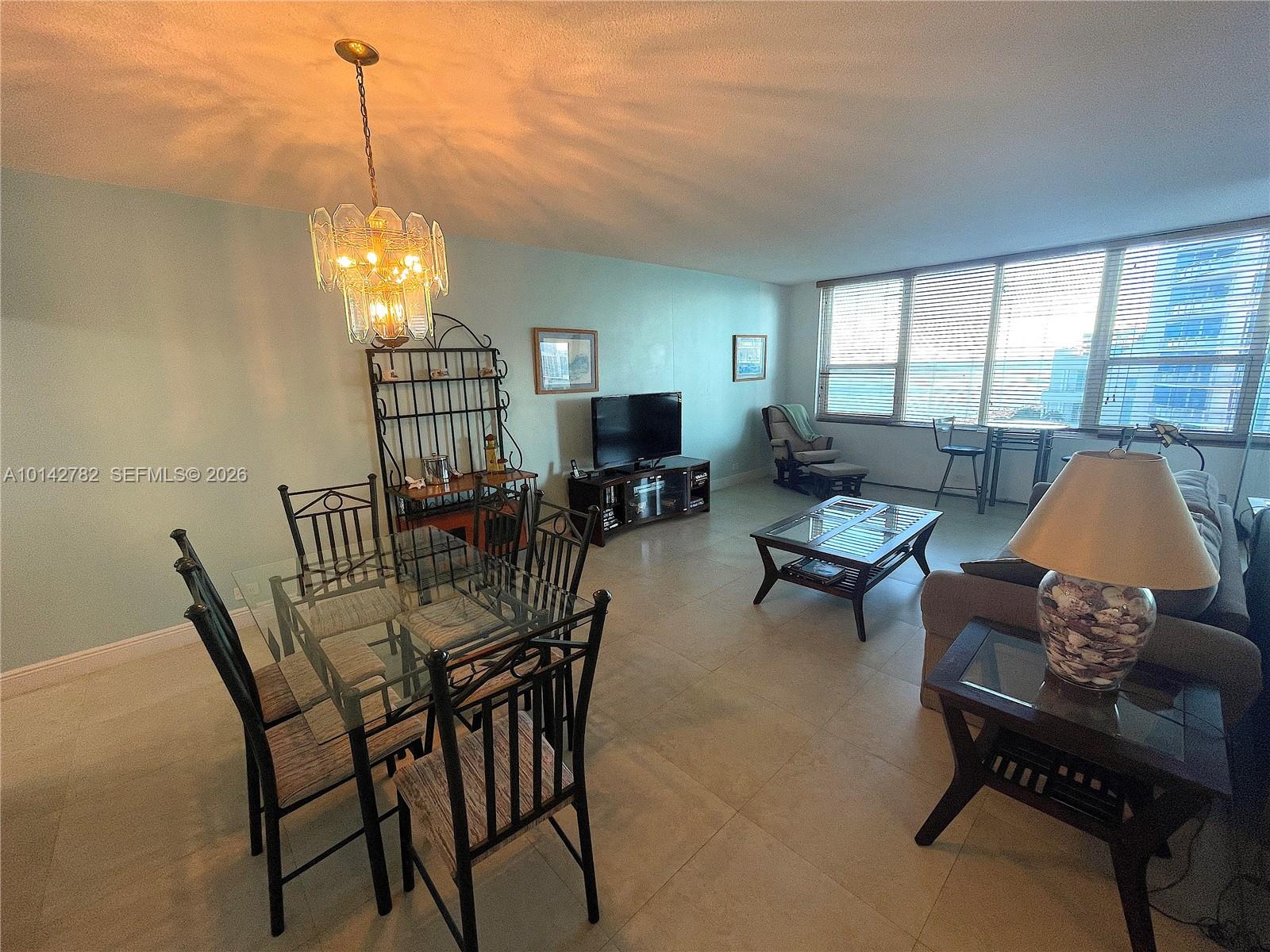A living and dining area features tile floors, a glass dining table, and large windows — 3505 S Ocean Dr # 1415, Hollywood FL 33019, HOLLYWOOD, FL
