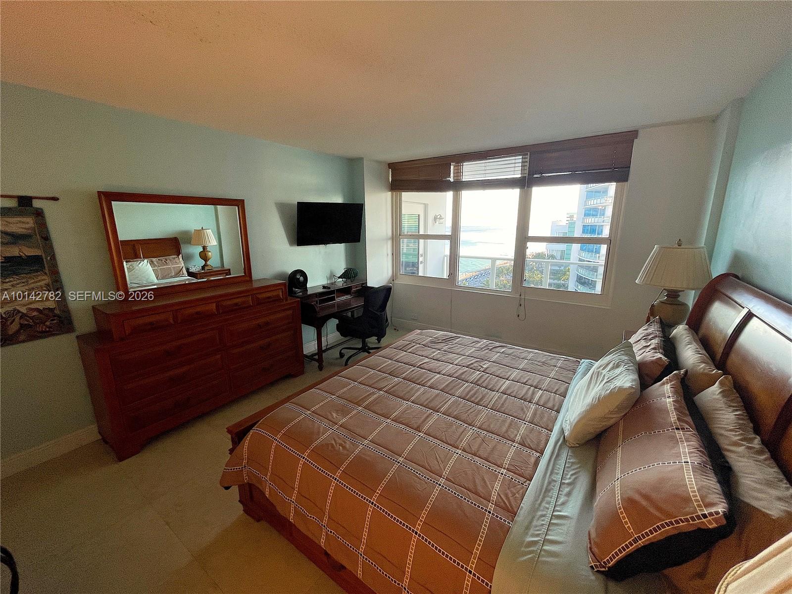 A bedroom features a wooden bed, a dresser with a mirror, and ocean views — 3505 S Ocean Dr # 1415, Hollywood FL 33019, HOLLYWOOD, FL