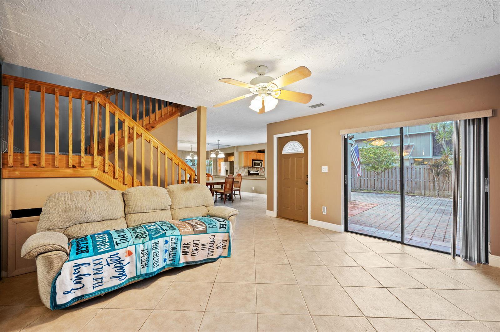 A living room features a beige sofa, tile flooring, a wooden staircase, and sliding glass doors — 620 Commodore Drive, Plantation FL 33325, PLANTATION, FL
