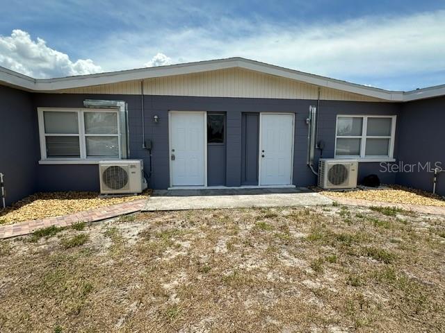 The exterior of a duplex features two white doors, two windows, and two air conditioning units — 27285 SUNNYBROOK ROAD, PUNTA GORDA, FL