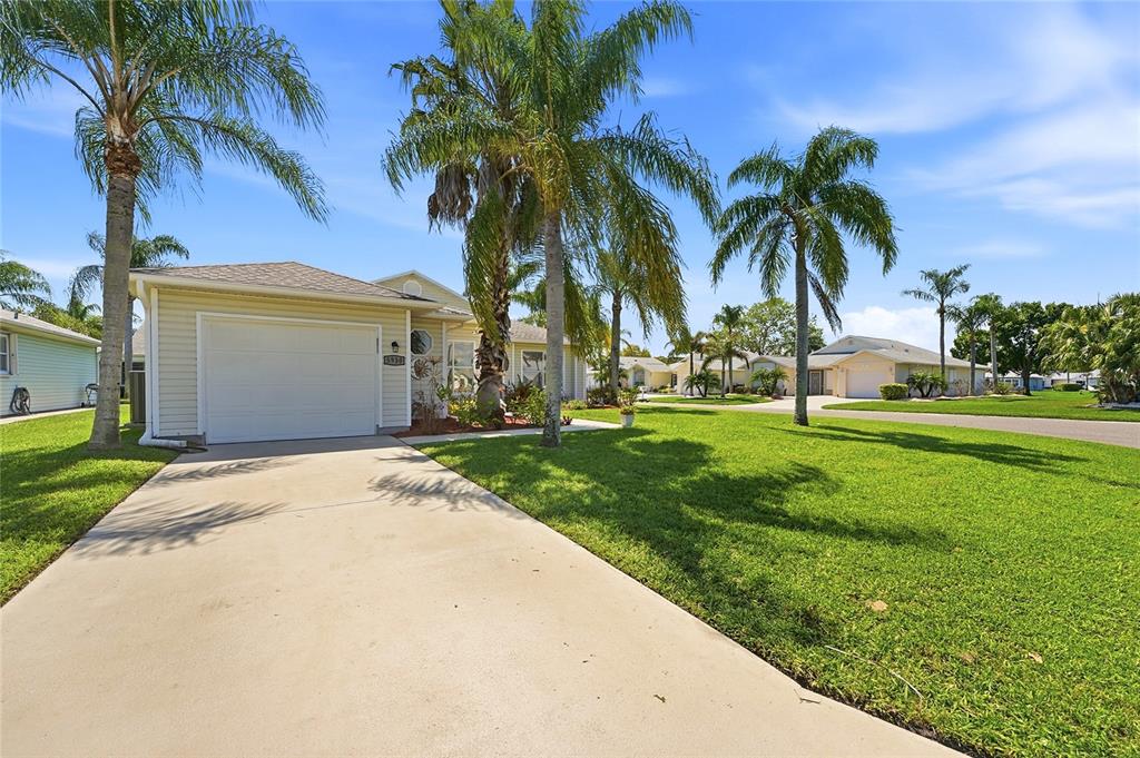 A single-story house with a white garage and palm trees sits on a grassy lawn — 5930 FOXTAIL WAY, FORT PIERCE, FL