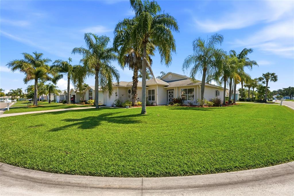 A single-story house with light siding and palm trees sits on a large corner lot — 5930 FOXTAIL WAY, FORT PIERCE, FL