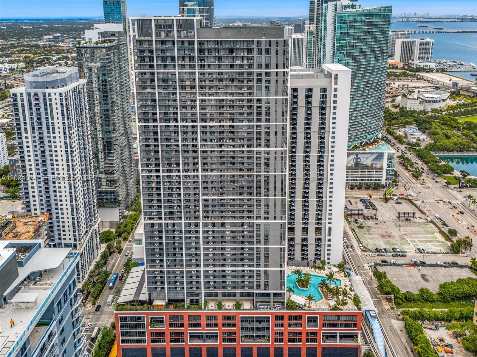 An aerial view of a tall residential skyscraper with a pool deck and surrounding buildings — 601 NE 1st Ave # 4814, Miami FL 33132, MIAMI, FL