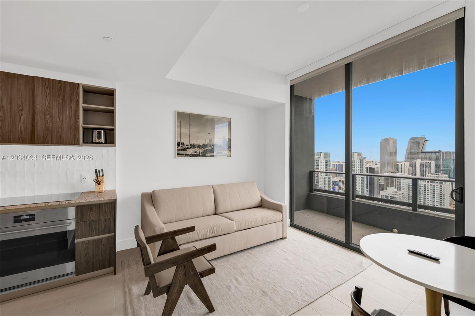 A modern studio apartment features a kitchenette, a beige sofa, and a balcony with city views — 601 NE 1st Ave # 4814, Miami FL 33132, MIAMI, FL