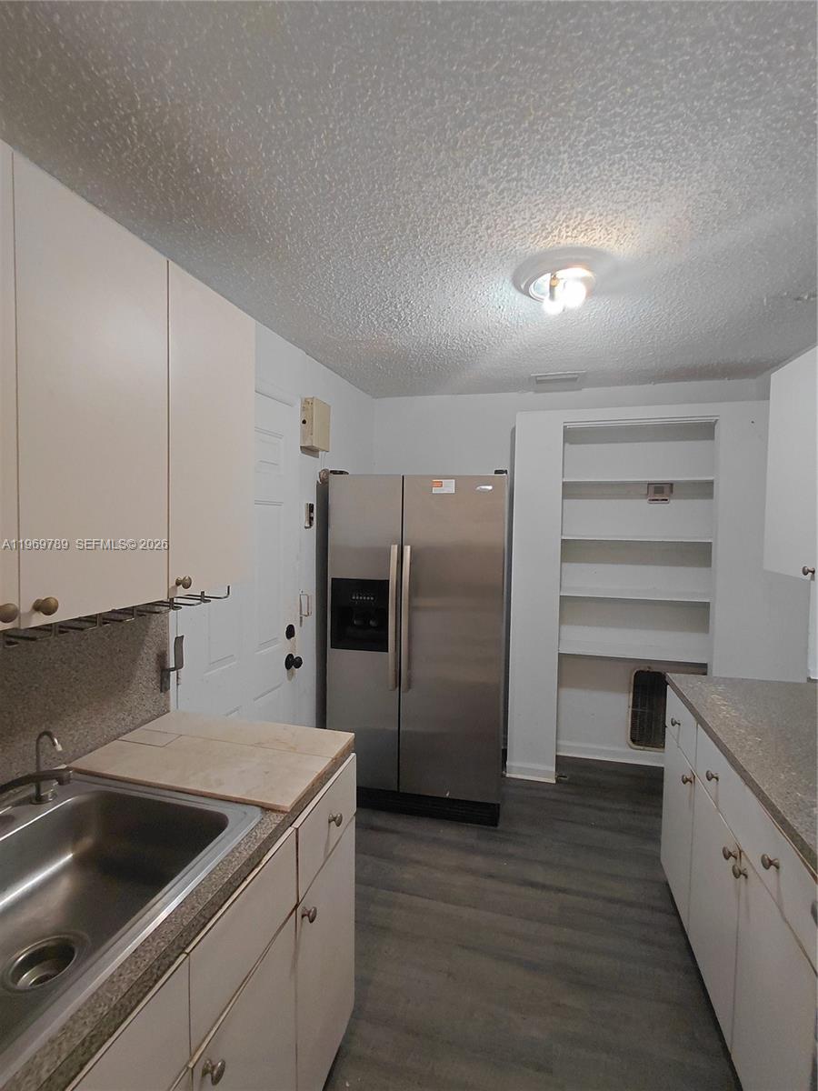 A kitchen features white cabinets, stainless steel appliances, open shelving, and gray wood-look flooring — 7091 NW 21st Ave, Miami FL 33147, MIAMI, FL
