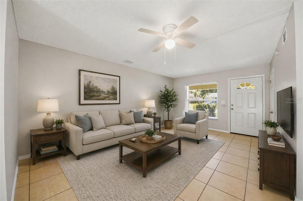 A living room features a beige sofa, armchair, coffee table, and tile flooring — 865 RICH DRIVE, OVIEDO, FL