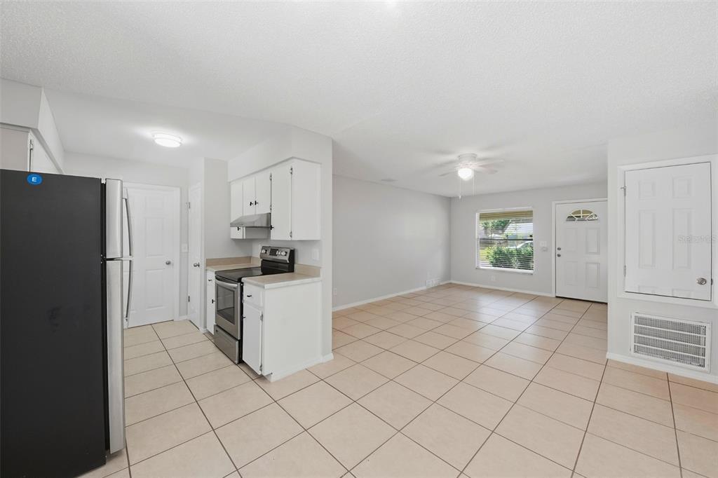 A kitchen with white cabinets and stainless steel appliances opens into a tiled living area — 865 RICH DRIVE, OVIEDO, FL