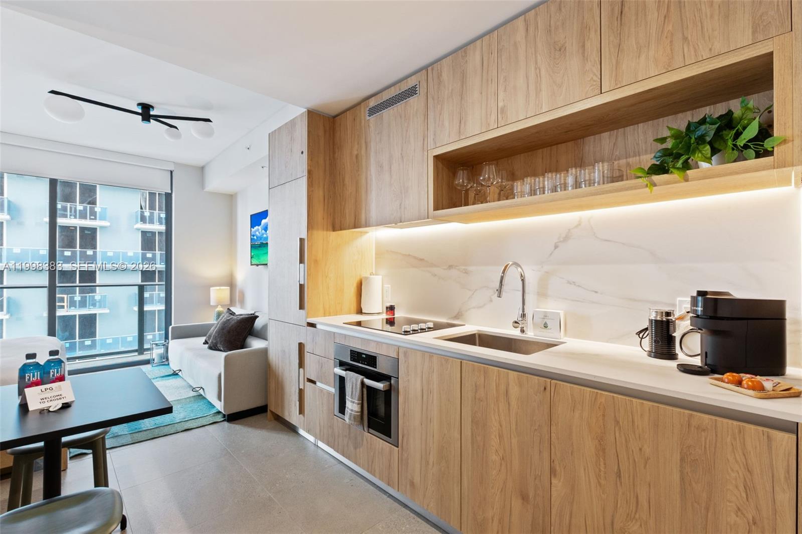 A modern kitchen features light wood cabinetry, white marble-style backsplash, and integrated appliances — 11 NE 6 # 2108, Miami FL 33132, MIAMI, FL