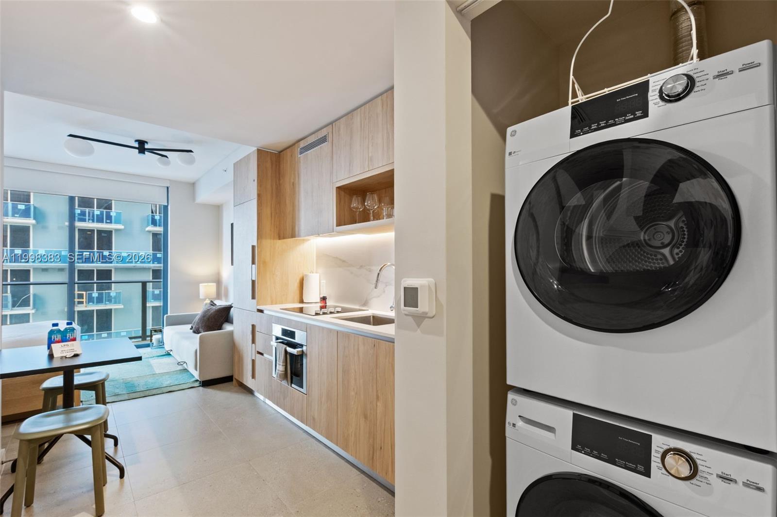 A compact kitchen with light wood cabinetry sits next to a stacked washer and dryer — 11 NE 6 # 2108, Miami FL 33132, MIAMI, FL