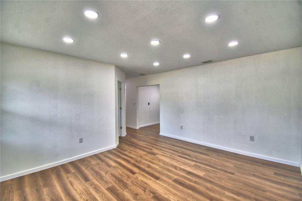 An empty room features white walls, recessed ceiling lights, and wood-look flooring — 109 2ND JPV STREET, WINTER HAVEN, FL