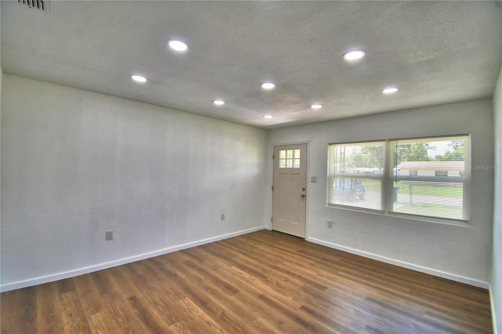 An empty room features light-colored walls, recessed ceiling lights, and wood-look flooring — 109 2ND JPV STREET, WINTER HAVEN, FL