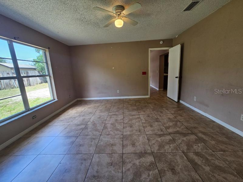 An empty room features tan walls, large square floor tiles, and a ceiling fan — 377 BRITTANY CIRCLE, CASSELBERRY, FL