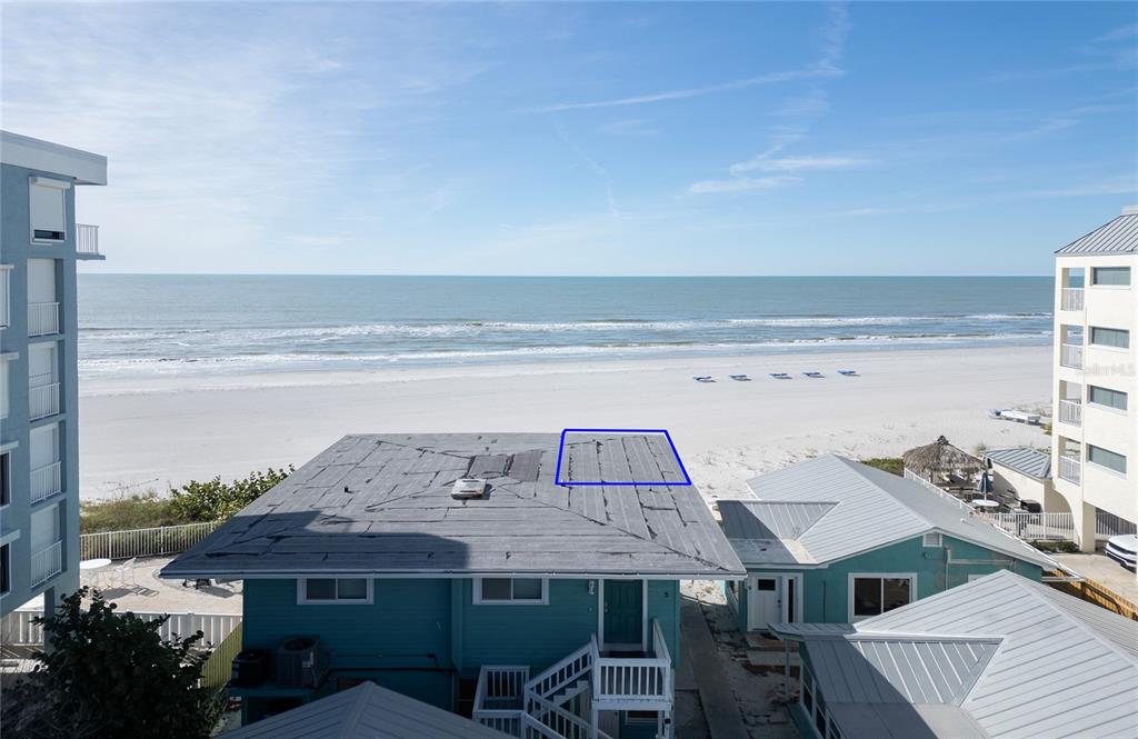 An elevated view shows a beach house with a weathered flat roof and oceanfront scenery — 19506 GULF BOULEVARD UNIT 4, INDIAN SHORES, FL