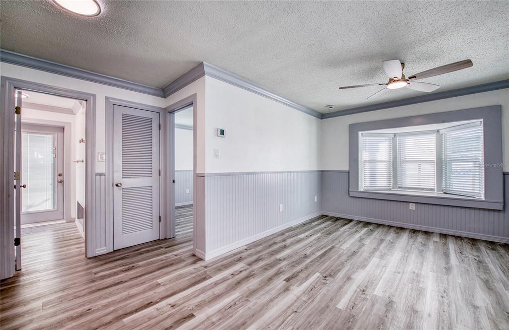 A room with wood-look flooring, gray wainscoting, a ceiling fan, and a bay window — 19506 GULF BOULEVARD UNIT 4, INDIAN SHORES, FL