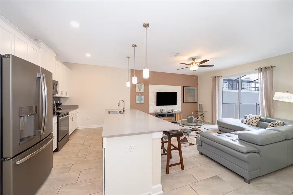 An open-concept kitchen with a large island and stainless steel appliances overlooks a living area — 4905 WINDERMERE AVENUE, KISSIMMEE, FL