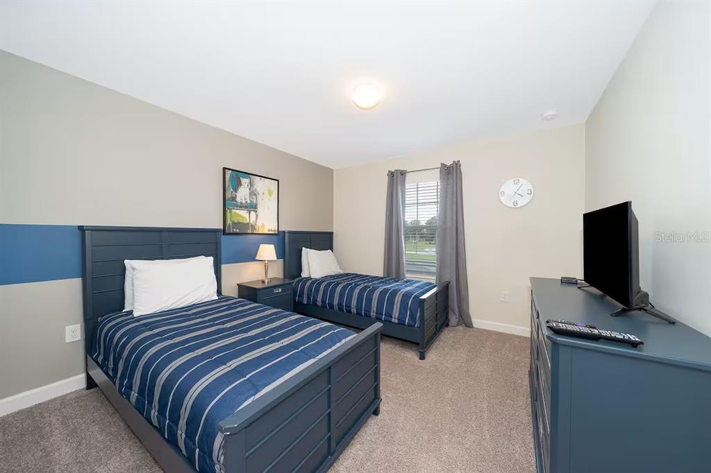 A bedroom features two twin beds with blue striped bedding and a dark blue dresser — 4905 WINDERMERE AVENUE, KISSIMMEE, FL