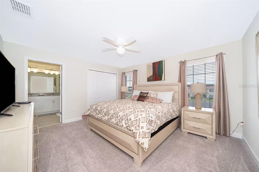 A bedroom features a bed with patterned bedding, two nightstands, and an attached bathroom — 4905 WINDERMERE AVENUE, KISSIMMEE, FL