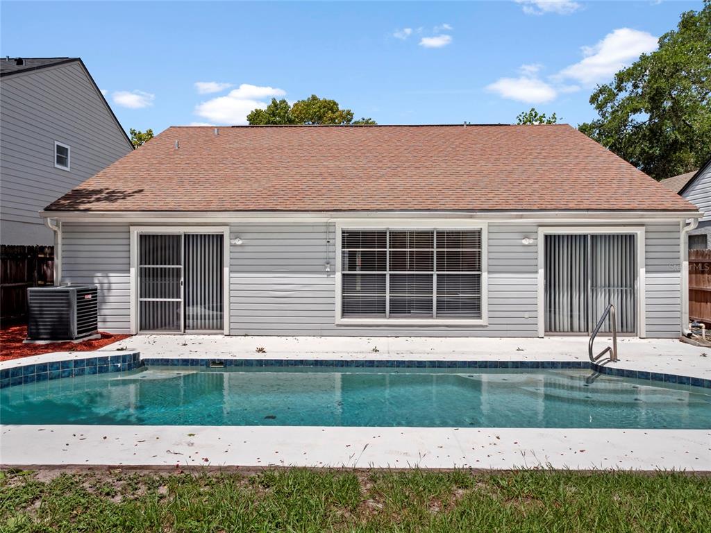 The exterior of a house features light gray siding, a brown roof, and a swimming pool — 605 WHITTINGHAM PLACE, LAKE MARY, FL