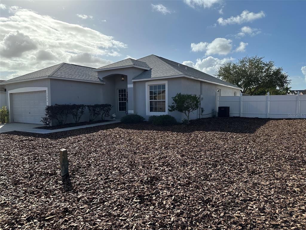 A single-story house with a gray exterior, a garage, and a wood-chip front yard — 1354 KNOLLWOOD DRIVE, DAVENPORT, FL