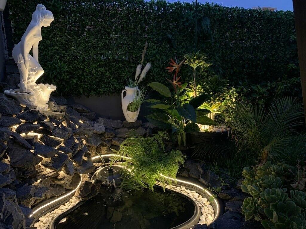 A small garden pond features a stone waterfall, a white statue, and integrated LED lighting — 16 Rua Encosta Dos Magos # B, FL