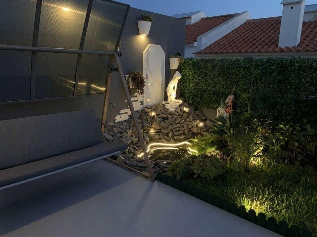 A patio at dusk features a swing, a stone rockery with a fountain, and landscaping — 16 Rua Encosta Dos Magos # B, FL