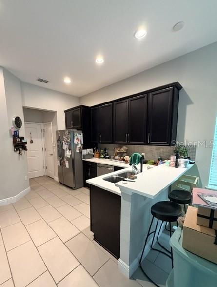 A kitchen features dark cabinets, stainless steel appliances, white countertops, and a breakfast bar — 9362 WOODCRANE DRIVE, WINTER GARDEN, FL
