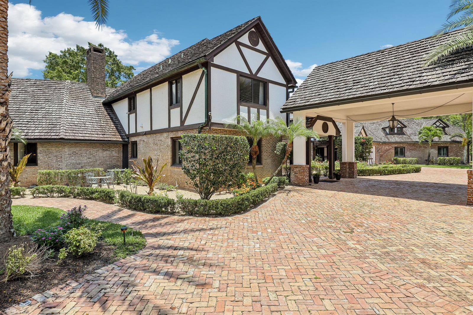 A Tudor-style house with a brick driveway and a covered porte-cochère entrance — 14900 Stirrup Lane, Wellington FL 33414, WELLINGTON, FL