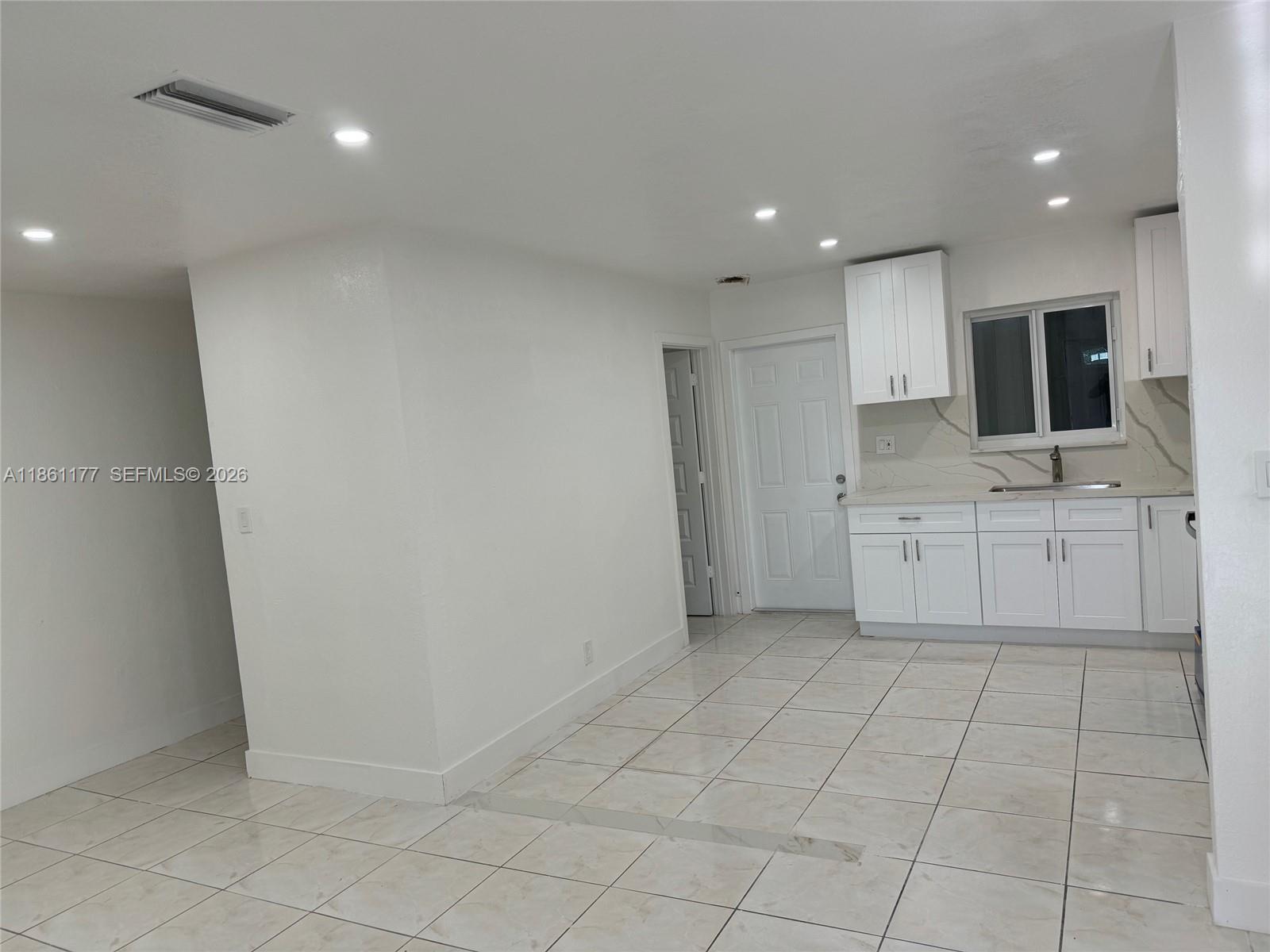 A kitchen features white shaker cabinets, stainless steel appliances, and marble-patterned countertops and backsplash — 732 SW 6th St # 732, Dania Beach FL 33004, DANIA BEACH, FL