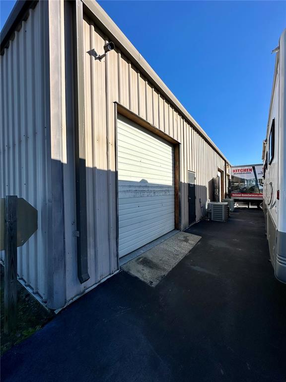 An exterior view of a metal warehouse building with a roll-up door and adjacent trailer — 1210-1232 DYER BOULEVARD UNIT 1218, KISSIMMEE, FL